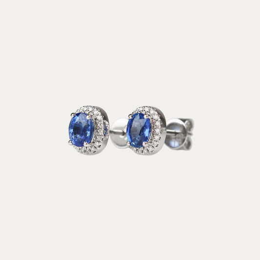 Pair of oval shaped cornflower sapphire earrings on a light gray background
