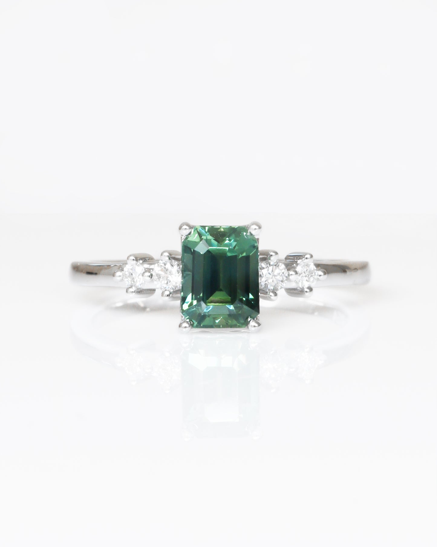 18k white gold teal Green sapphire ring with diamond accents on a white background