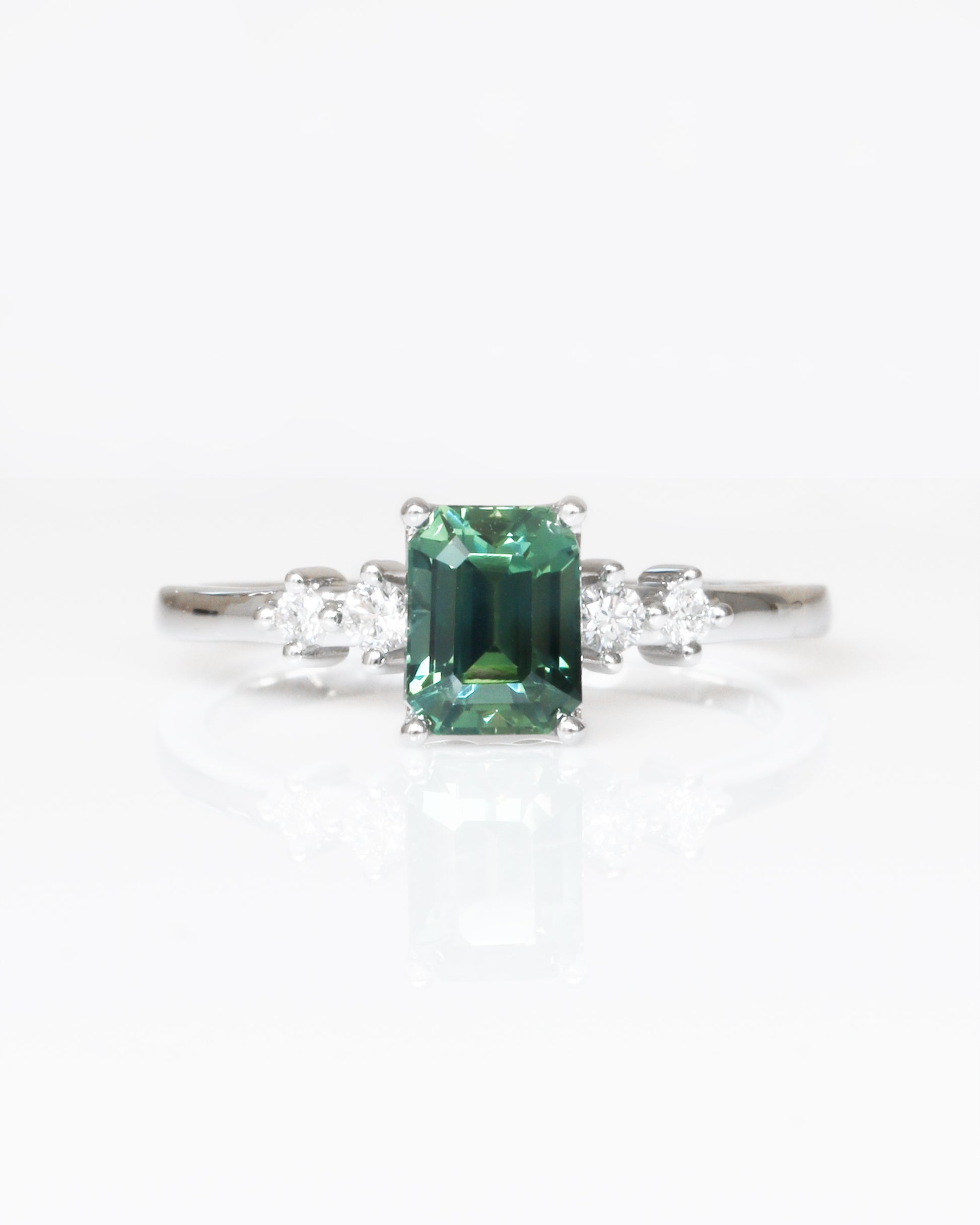 18k white gold teal Green sapphire ring with diamond accents on a white background