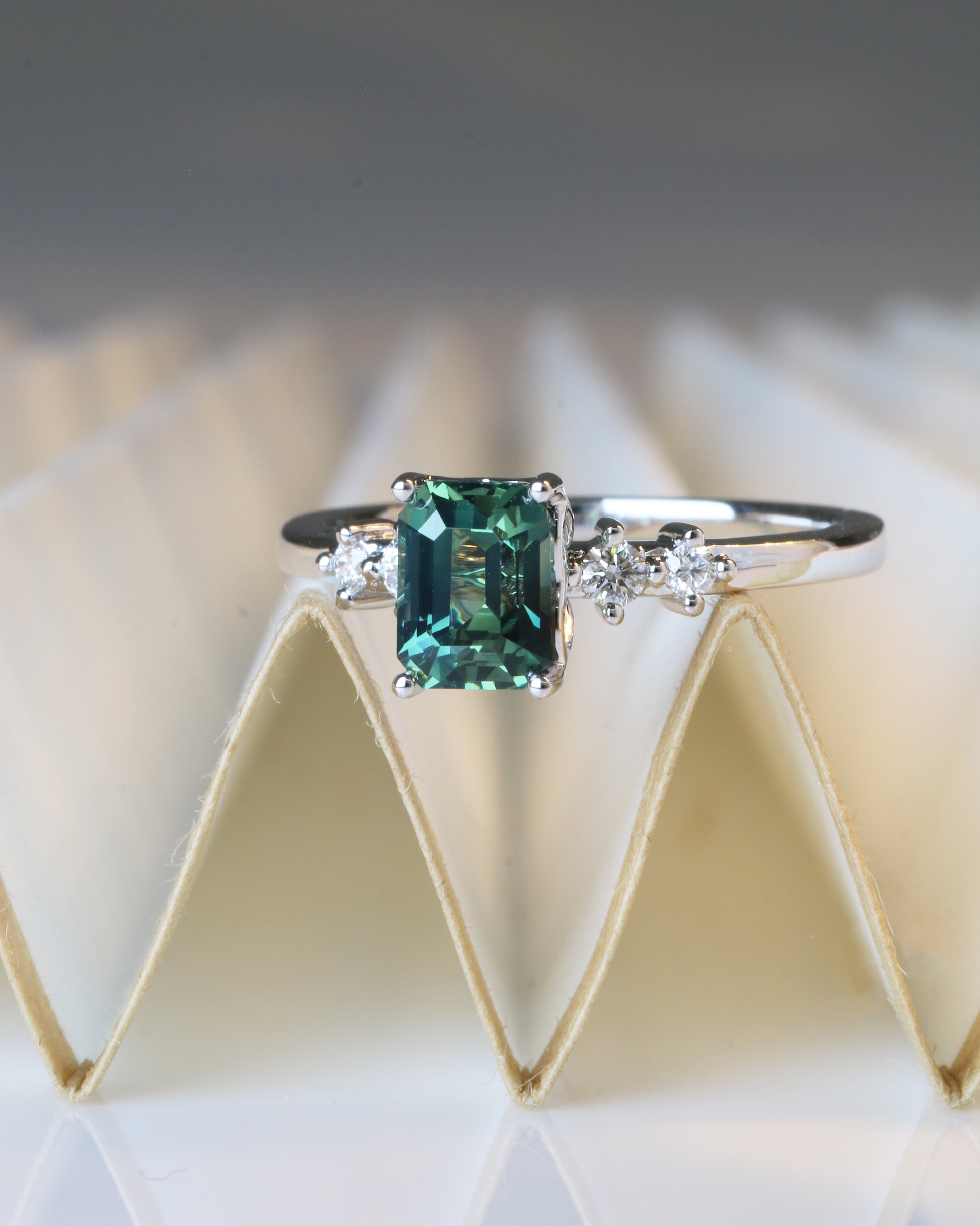 18k white gold teal Green sapphire ring  on a textured white background