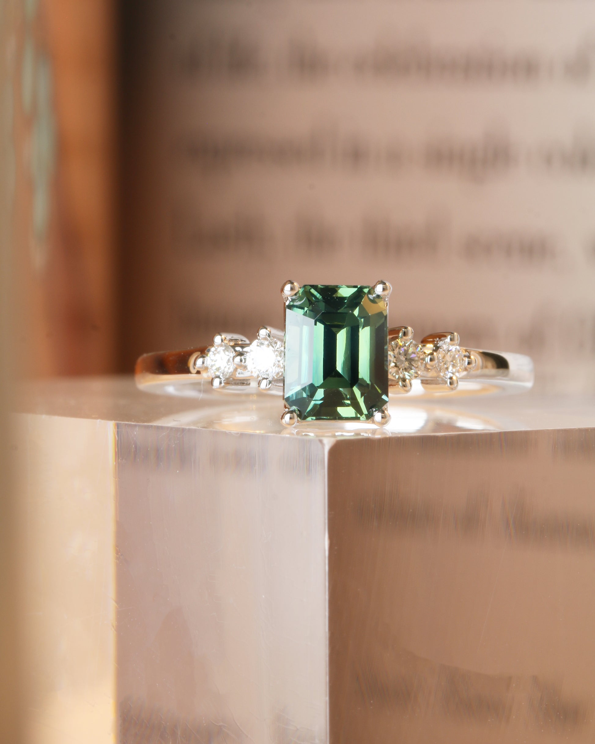 18k white gold teal Green sapphire ring   on a reflective surface