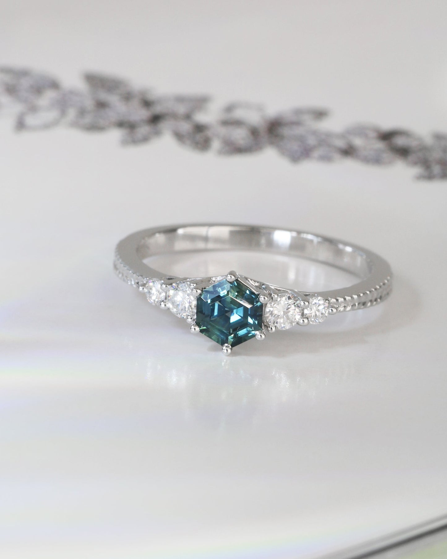 18k white gold blue green teal sapphire ring on a white surface