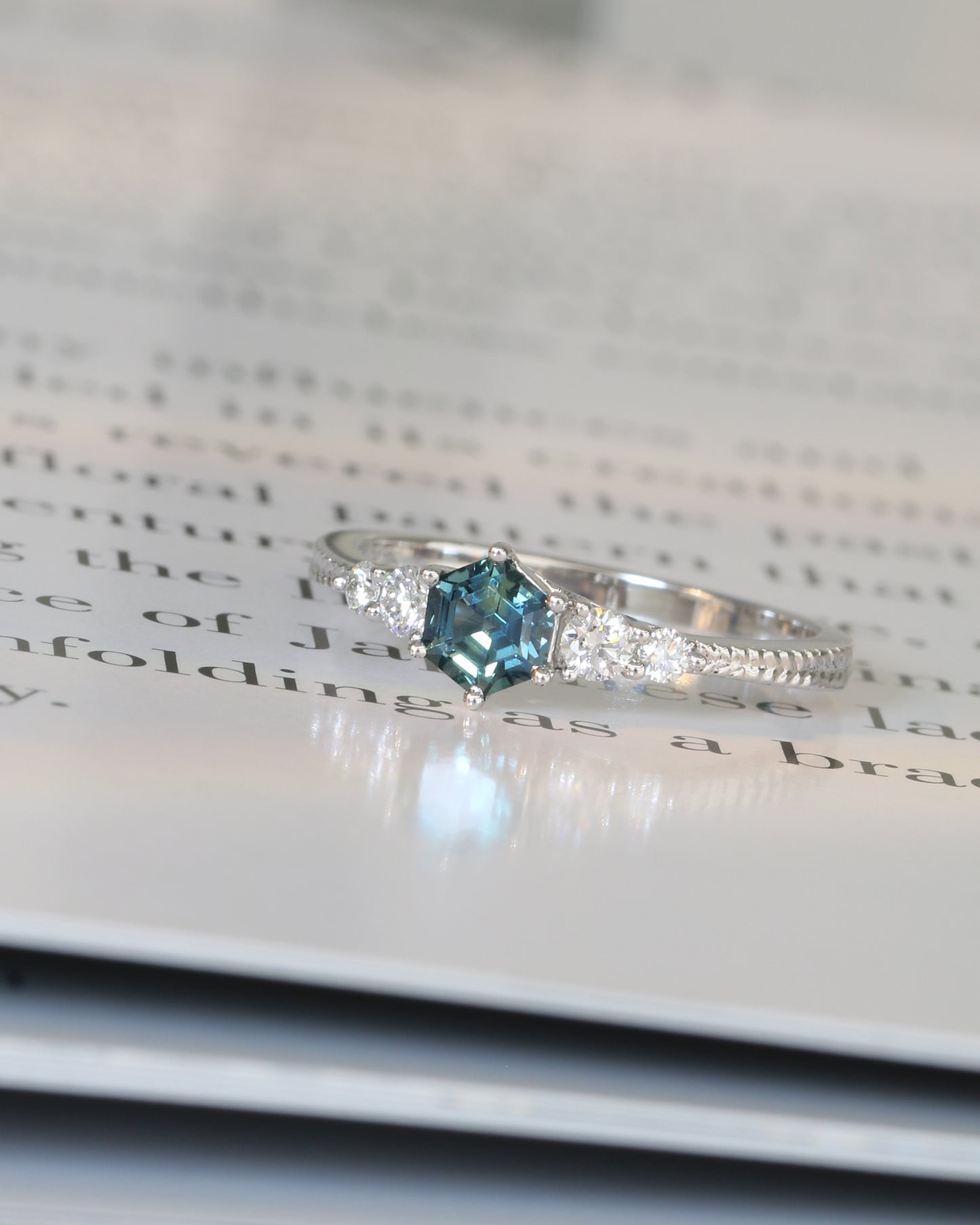 18k white gold blue green teal sapphire ring on an open book