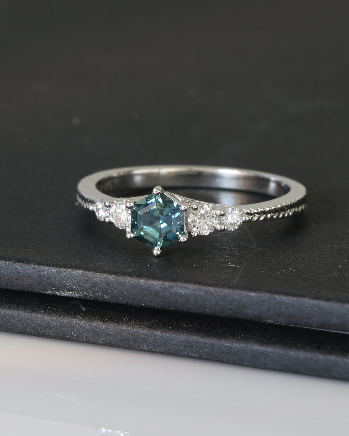 18k white gold blue green teal sapphire ring on a dark surface