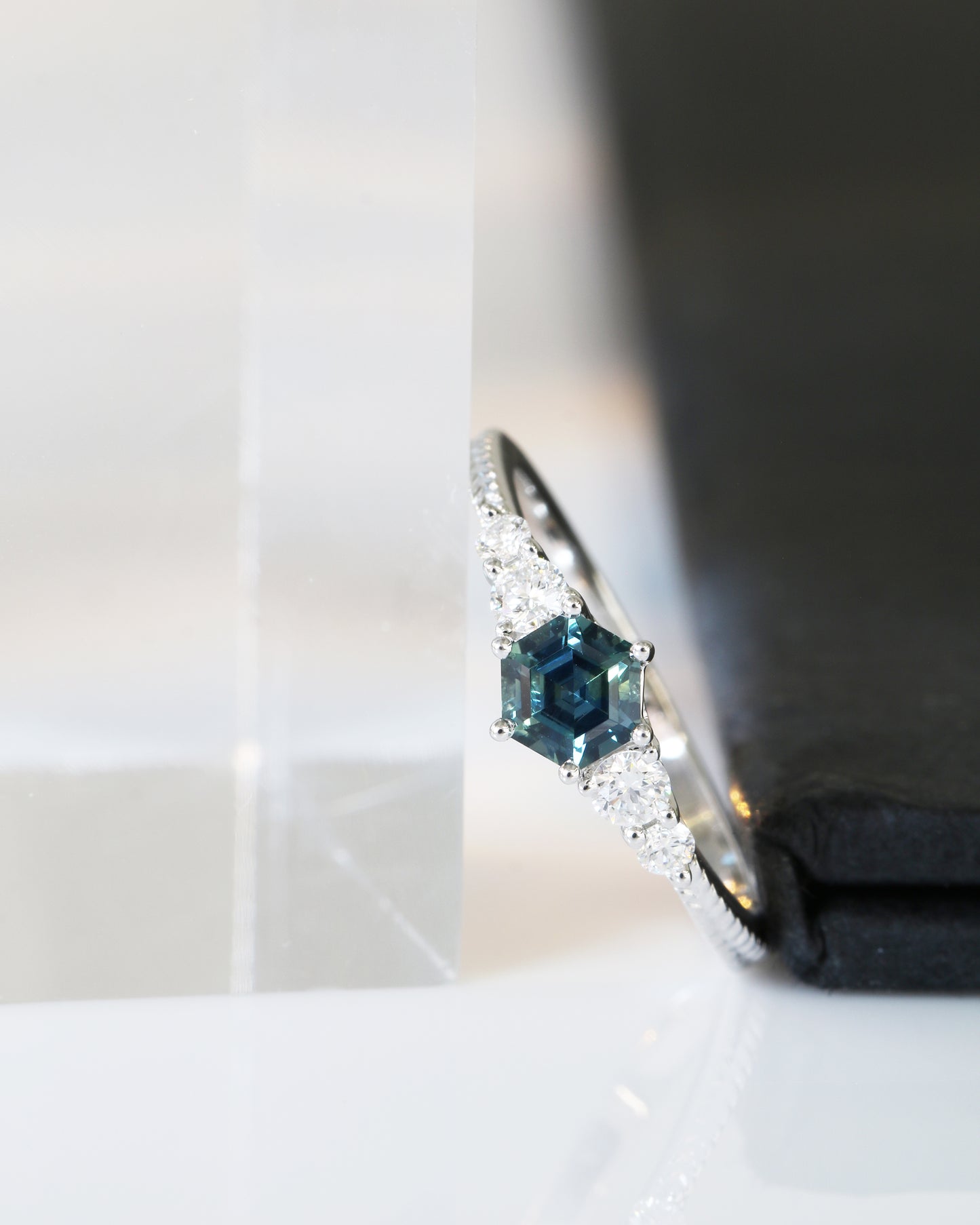 Close-up of 18k white gold blue green teal sapphire ring on a white background