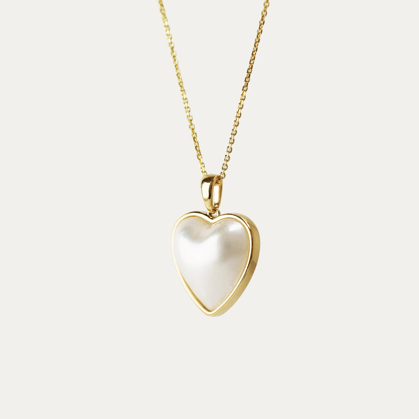 Heart-shaped pendant with gold frame on a light gray background