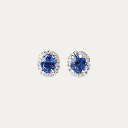 Pair of oval shaped cornflower sapphire earrings on a light gray background
