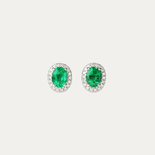 Pair of emerald earrings with halo diamond accents on a light gray background