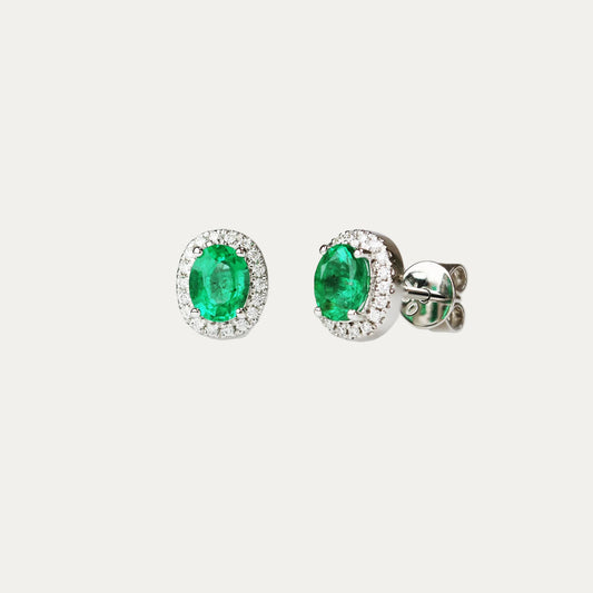 Pair of emerald earrings with halo diamond accents on a light gray background