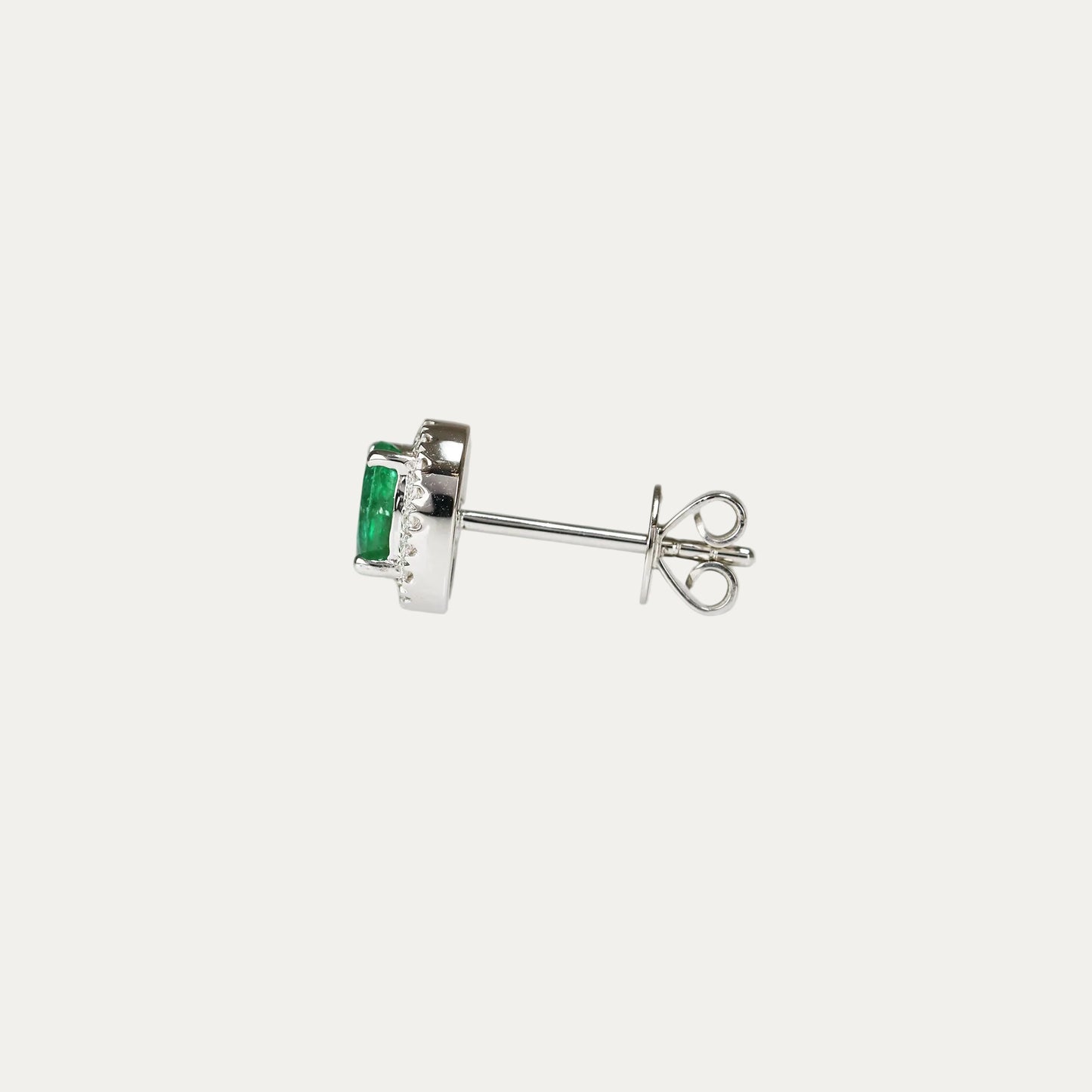 Pair of emerald earrings with halo diamond accents on a light gray background