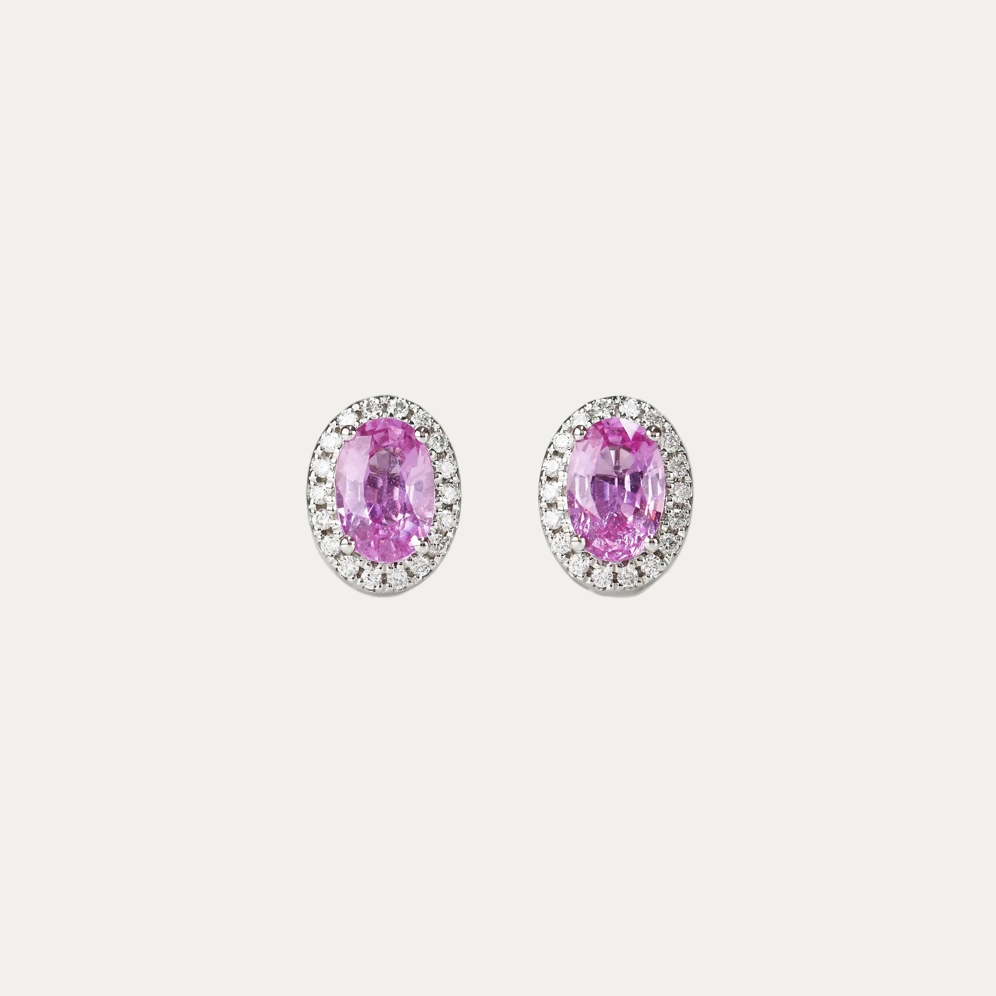 Pair of oval-shaped pink sapphire halo diamond earrings on a gray background