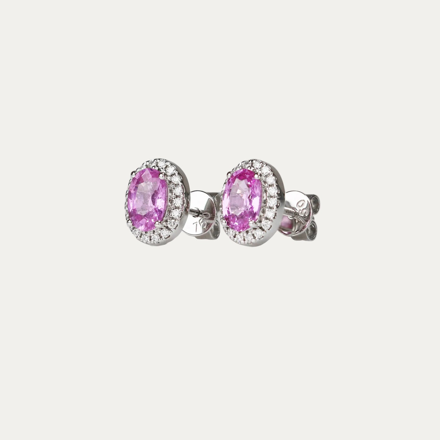 Pair of oval-shaped pink sapphire halo diamond earrings on a gray background