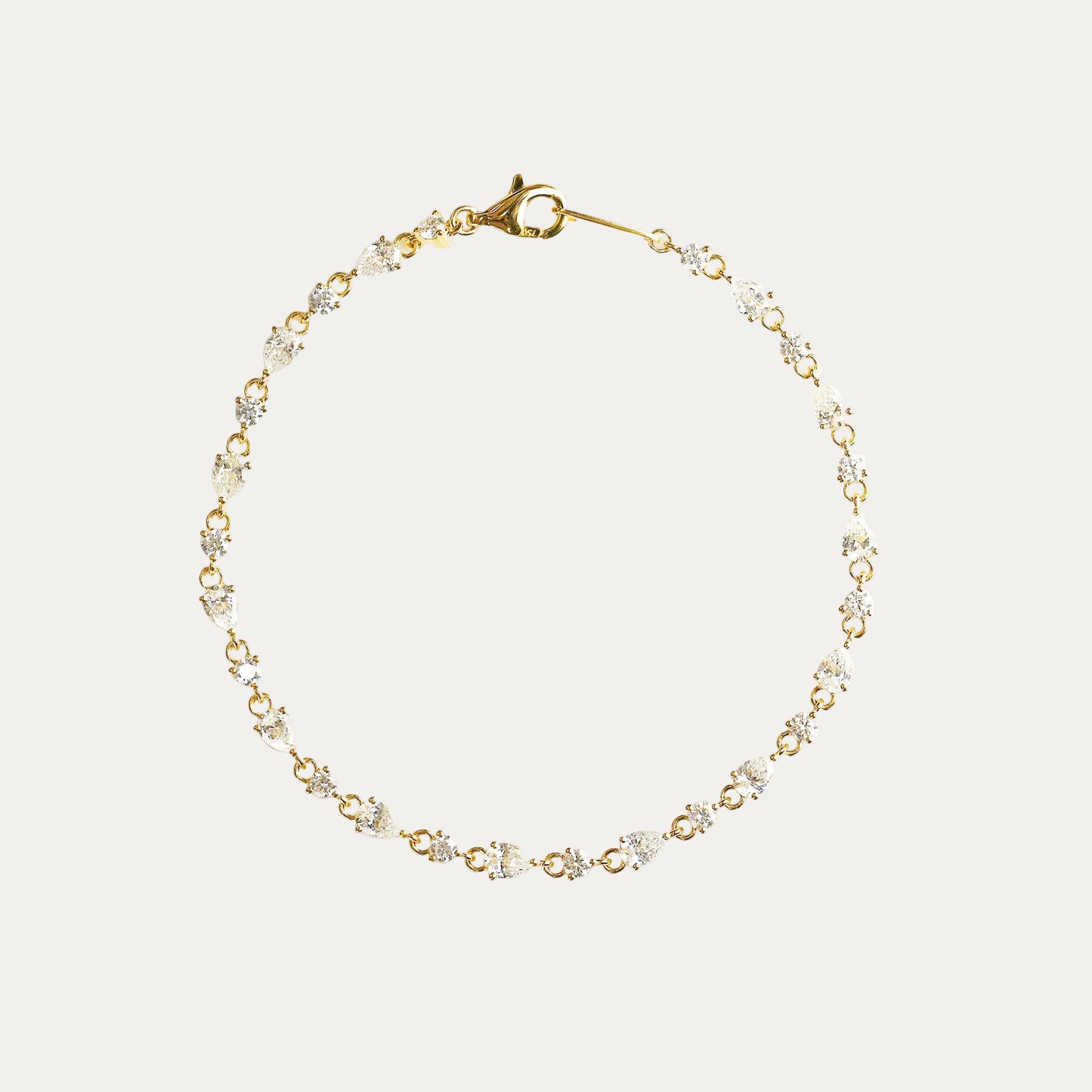 18k yellow Gold pear and round diamond bracelet on a white background