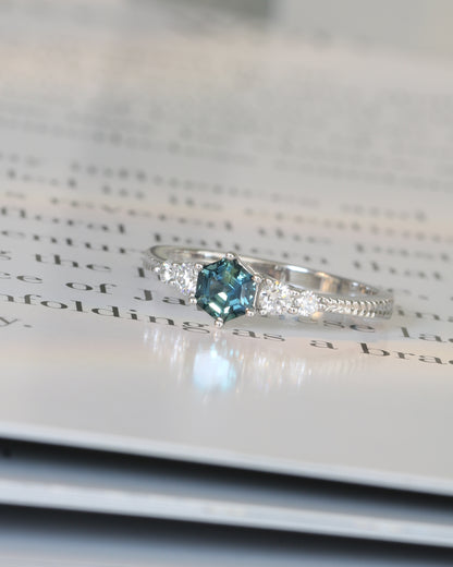 18k white gold blue green teal sapphire ring on an open book