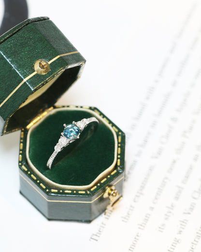 18k white gold blue green teal sapphire ring in a green jewelry box on a white background