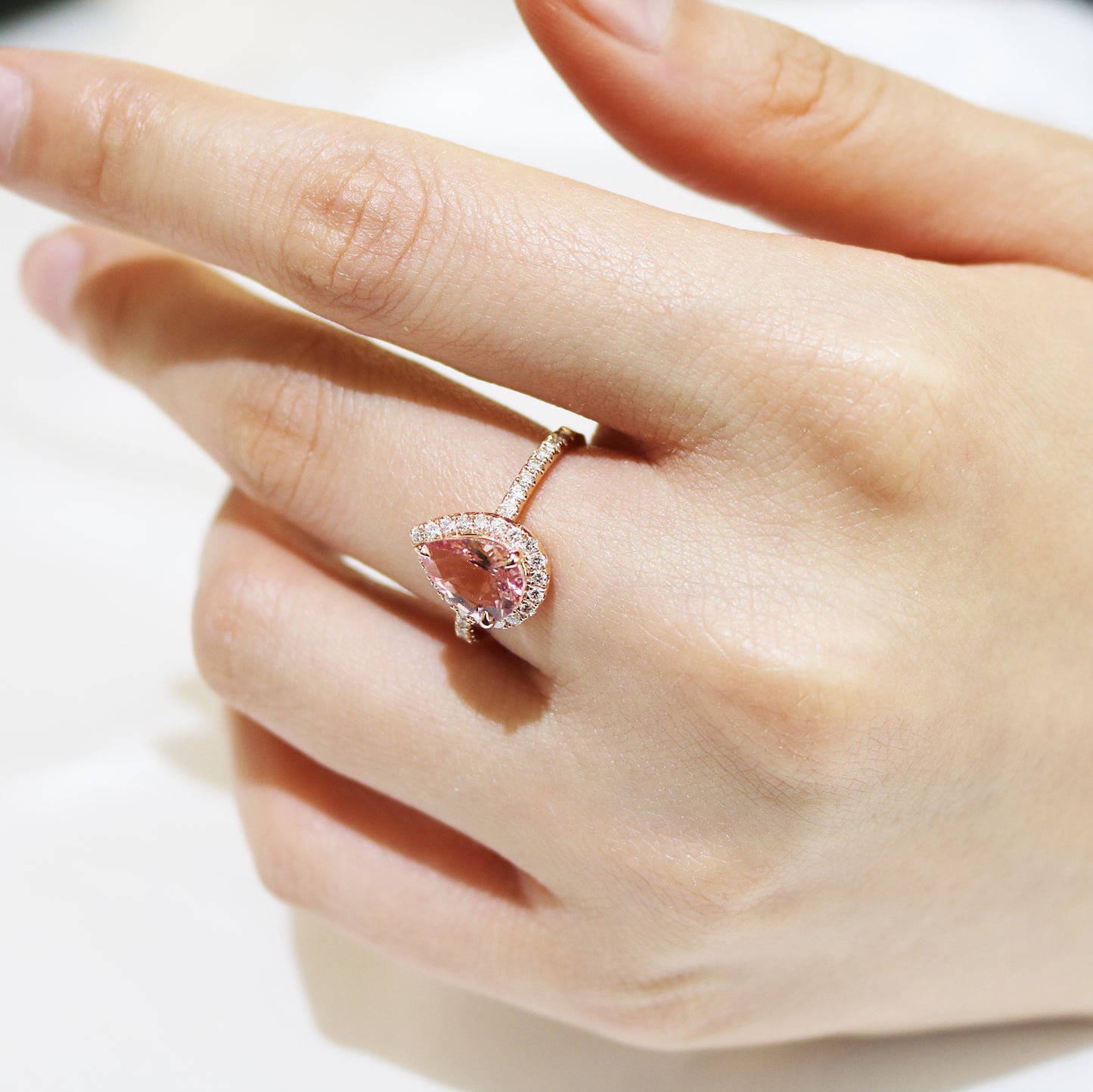 18k玫瑰金粉光環梨形切割粉紅摩根石鑽石戒指在中指上 18k Rose Gold Pear Shape Morganite Halo Diamond Ring on middle finger
